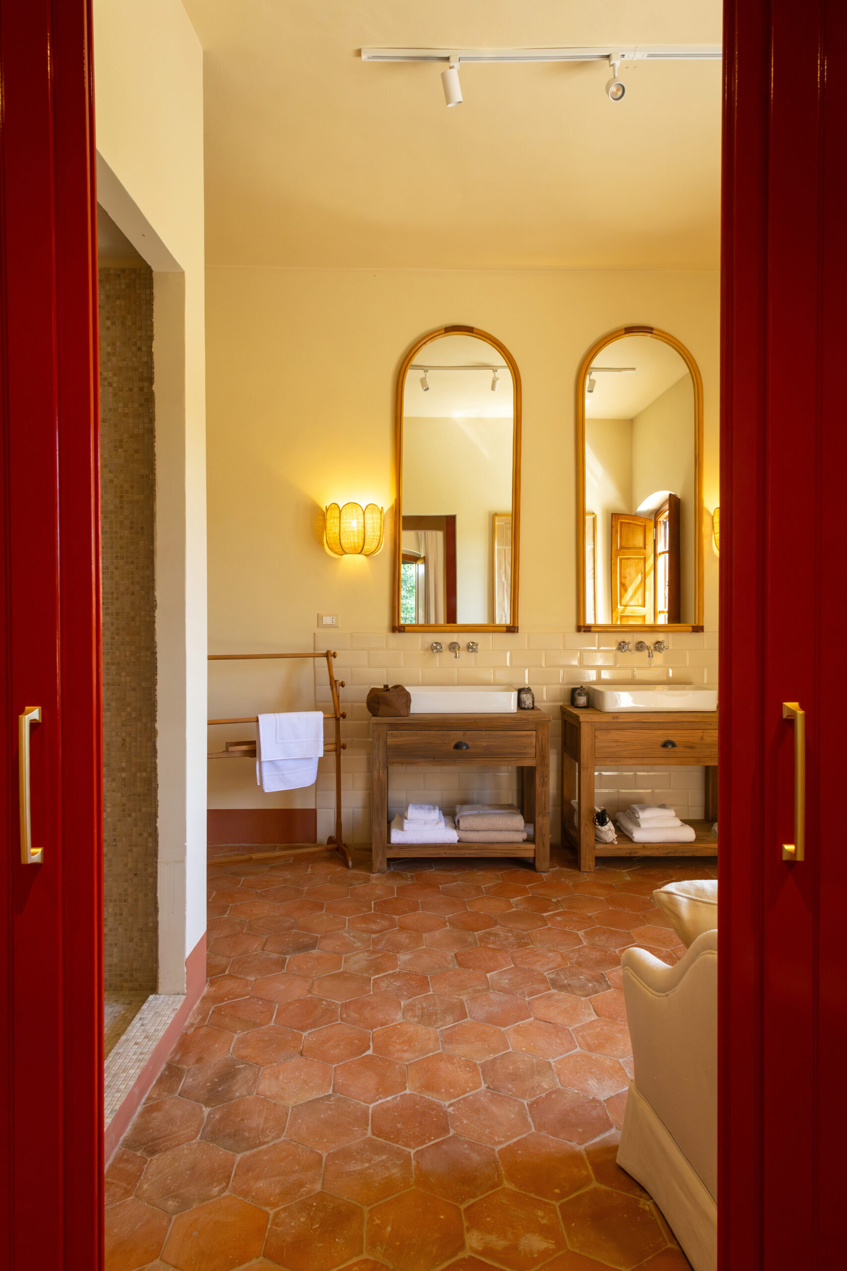 Bagno di Villa Piaggia con doppio lavabo, specchiere ad arco e pavimento in cotto