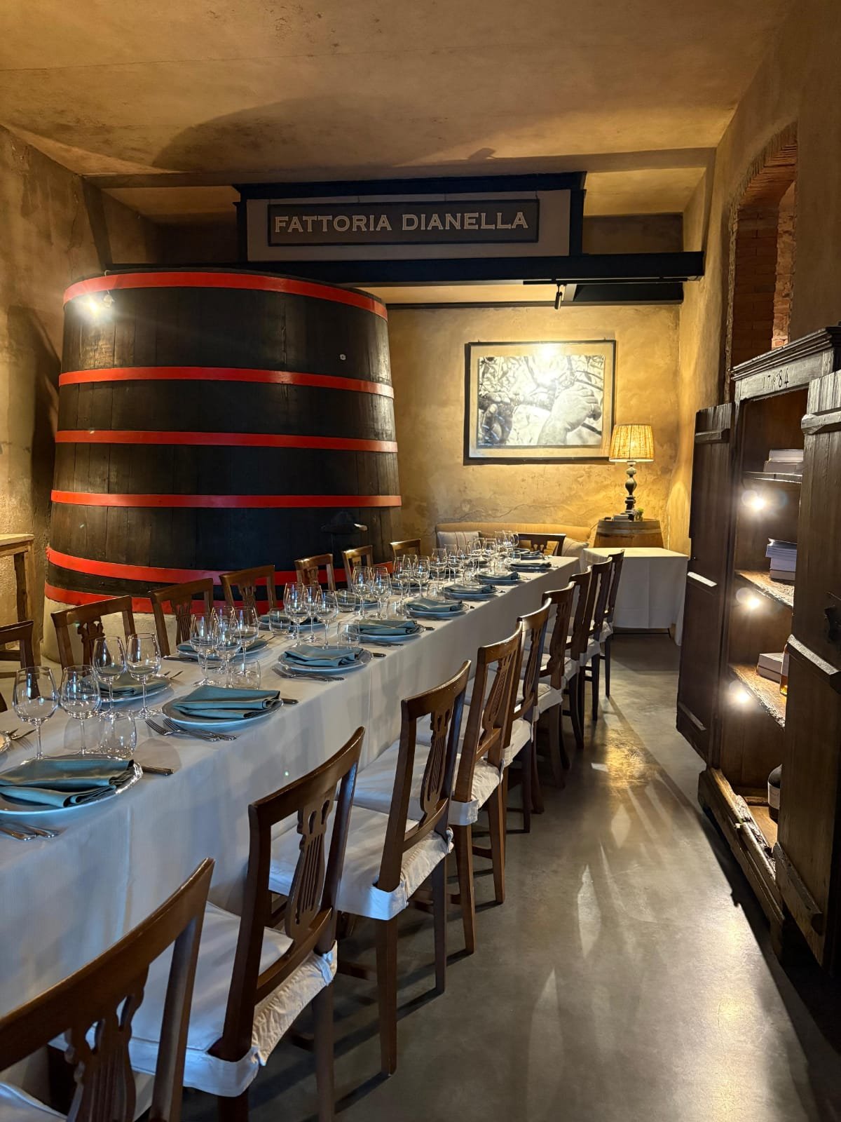 Tavolata imbandita nelle cantine storiche di Villa Dianella, con botte e insegna Fattoria Dianella