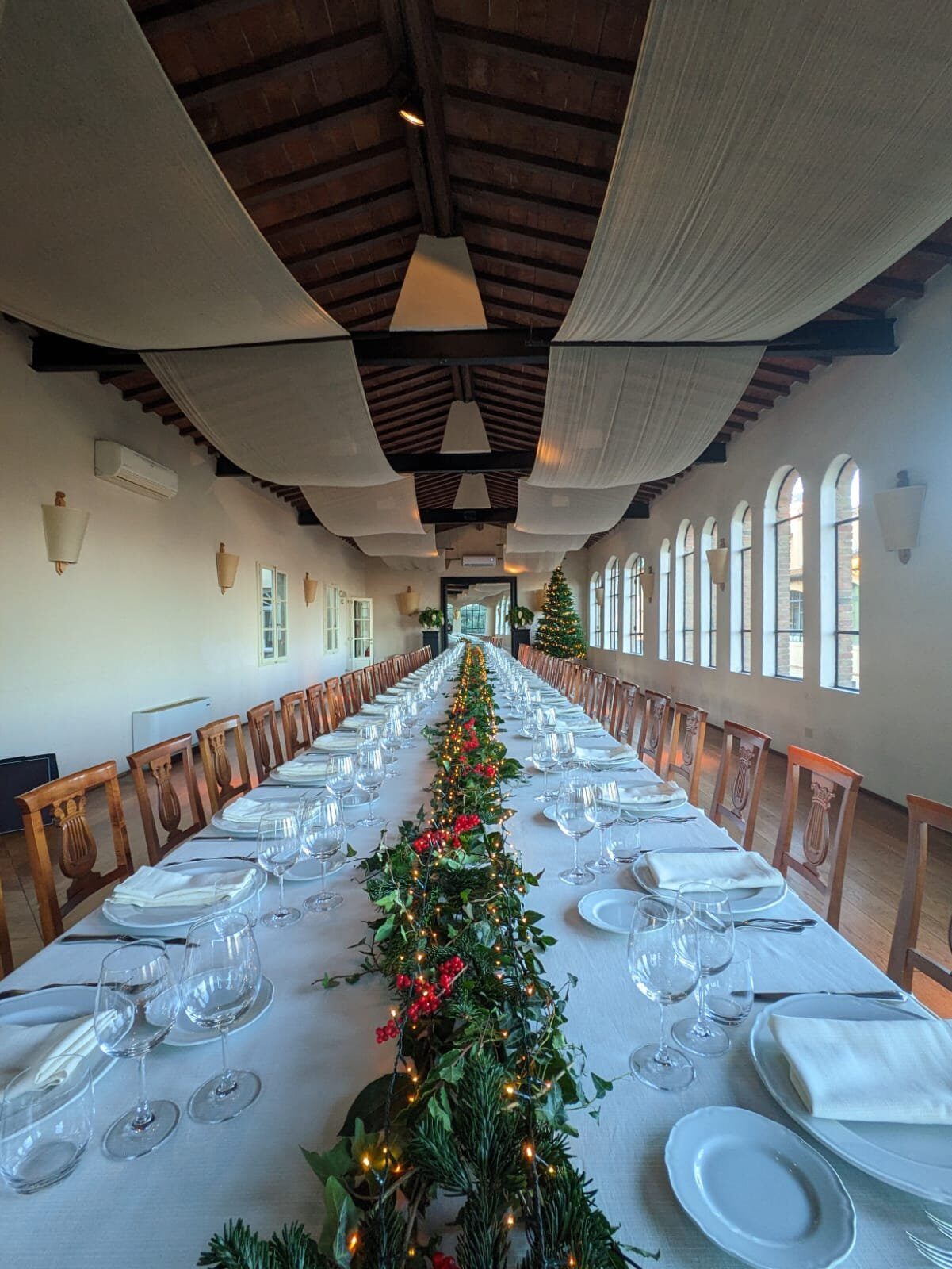 Lunga tavolata imbandita con ghirlanda natalizia e lucine, albero di Natale sullo sfondo, sala del Granaio di Villa Dianella