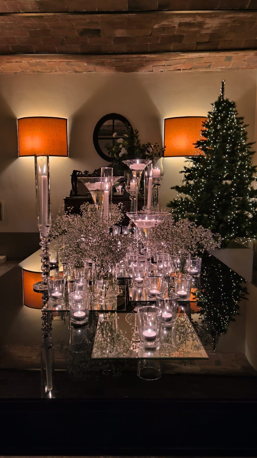 Composizione natalizia con candele, fiori bianchi e albero di Natale illuminato a Villa Dianella