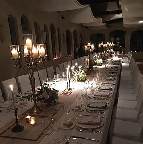 Tavolata imbandita a lume di candela con candelabri e fiori rossi per una cena di Natale a Villa Dianella