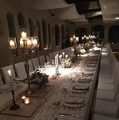Tavolata imbandita a lume di candela con candelabri e fiori rossi per una cena di Natale a Villa Dianella