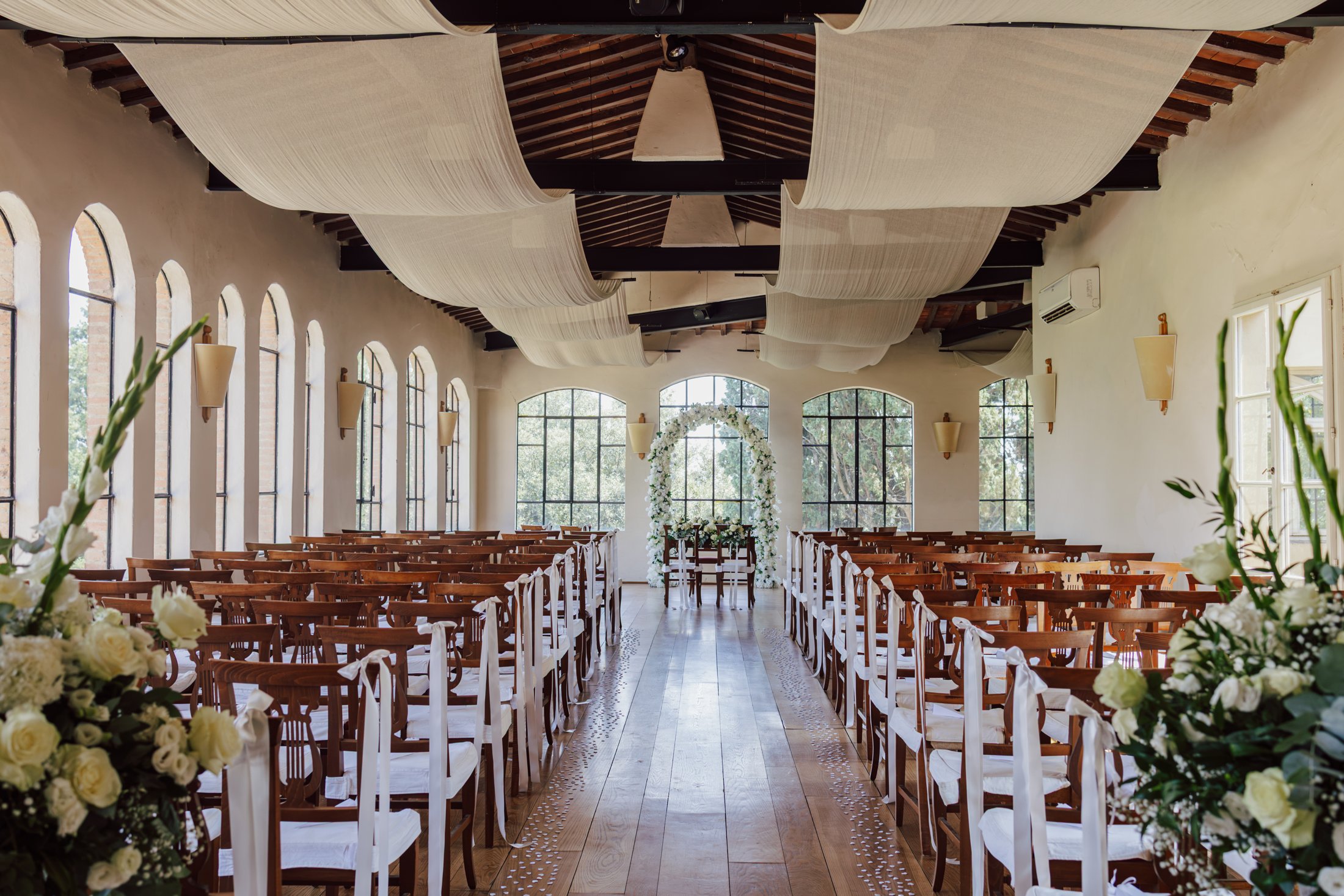 Sala della cerimonia di Villa Dianella allestita con arco floreale bianco, vista dal fondo