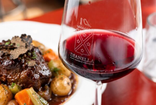 Guancia di manzo brasata al Chianti con lamelle di tartufo e verdure stufate, accanto a un calice di vino rosso Dianella